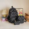 A set of black nylon travel backpacks featuring a cute white bow print, displayed on a light surface.