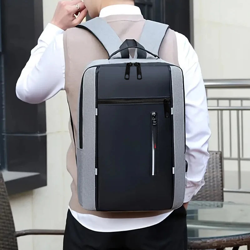 A person wearing a white shirt is shown from behind carrying a gray and black durable laptop backpack.