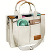 A beige canvas tote handbag with light brown leather accents and a green fan inside.