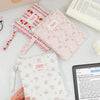 A light pink floral plaid cotton tablet pouch is shown next to a red patterned version and a wooden item on a white surface.