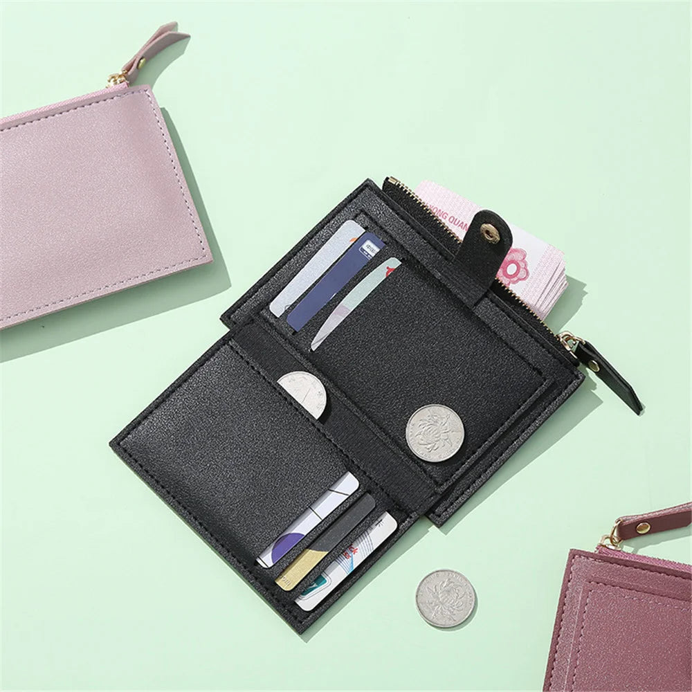 A black mini card holder wallet and a pink card holder are displayed on a light green surface.