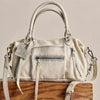 A cream-colored vintage PU leather crossbody tote bag with adjustable straps resting on a wooden surface.