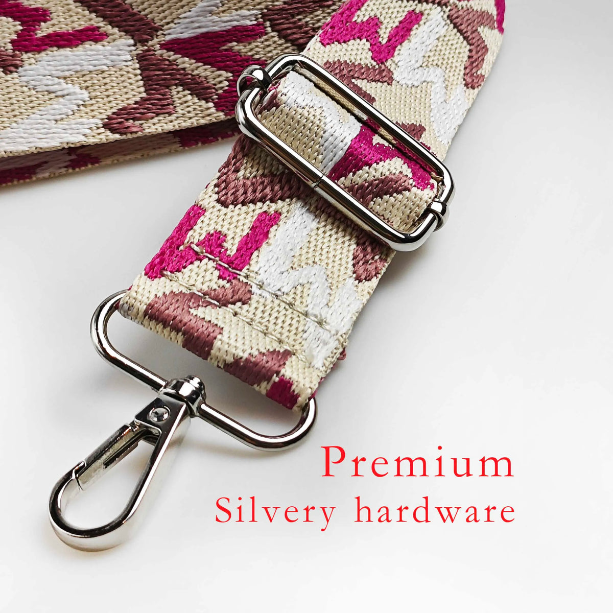 Close-up of a pink and cream jacquard patterned strap with silver hardware for an adjustable crossbody bag.
