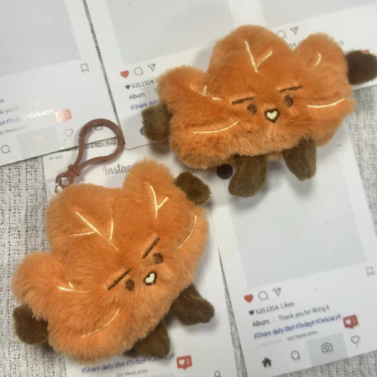 A fluffy orange maple leaf plush toy with brown accents, displayed on a white background.