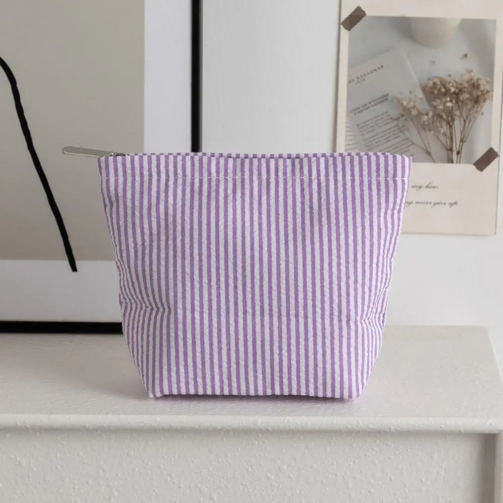 Pochette en crochet à rayures violettes posée sur une surface blanche à côté d'une photo encadrée.