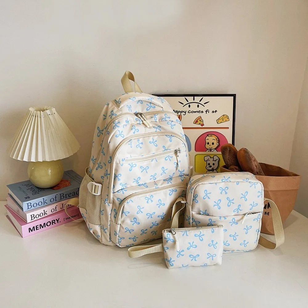 A set of cute bow print nylon travel backpacks displayed on a white surface next to a framed picture and a potted plant.
