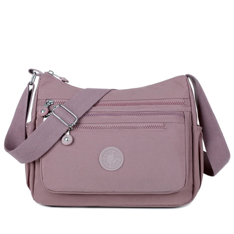 A mauve waterproof nylon crossbody shoulder bag with a strap and flap.