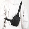 Bolso cruz impermeable negro de pecho usado sobre el torso de una persona.