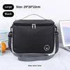 A black insulated portable lunch bag with a shoulder strap is shown on a white surface.