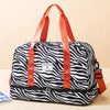 An orange nylon travel duffle bag with a black and white zebra stripe pattern.
