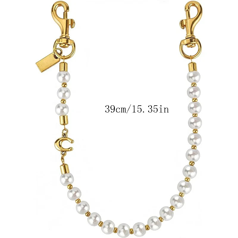Gold letter charm necklace with white pearls and a clasp.