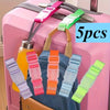 Five multi-color adjustable luggage straps with buckles are displayed on a pink suitcase.