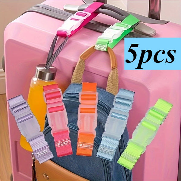 Five multi-color adjustable luggage straps with buckles are displayed on a pink suitcase.