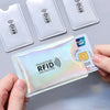 Una mano sostiene una funda bloqueadora de RFID, mostrando una tarjeta de pago y varias fundas en blanco.