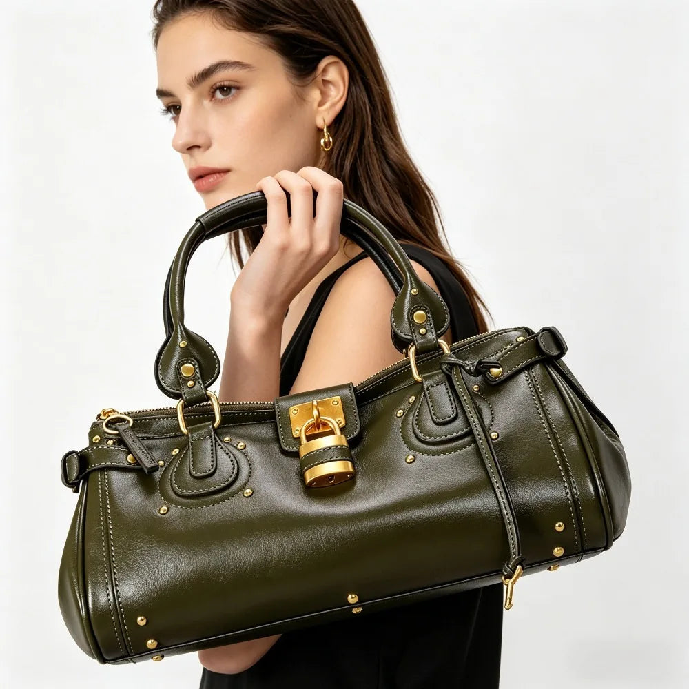 A woman holds a dark olive green vegan leather tote bag with gold hardware.