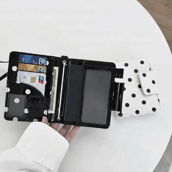 A black polka dot passport holder displaying multiple card slots and a clear ID card.