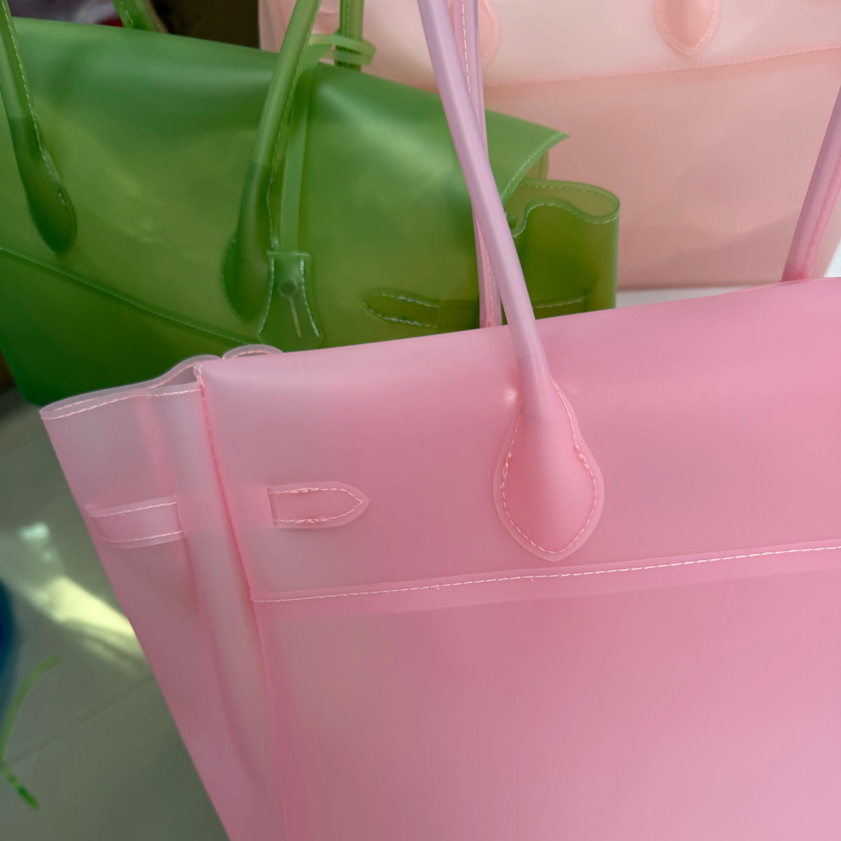 Gros plan d'un sac fourre-tout en gelée rose transparent à côté d'un vert.