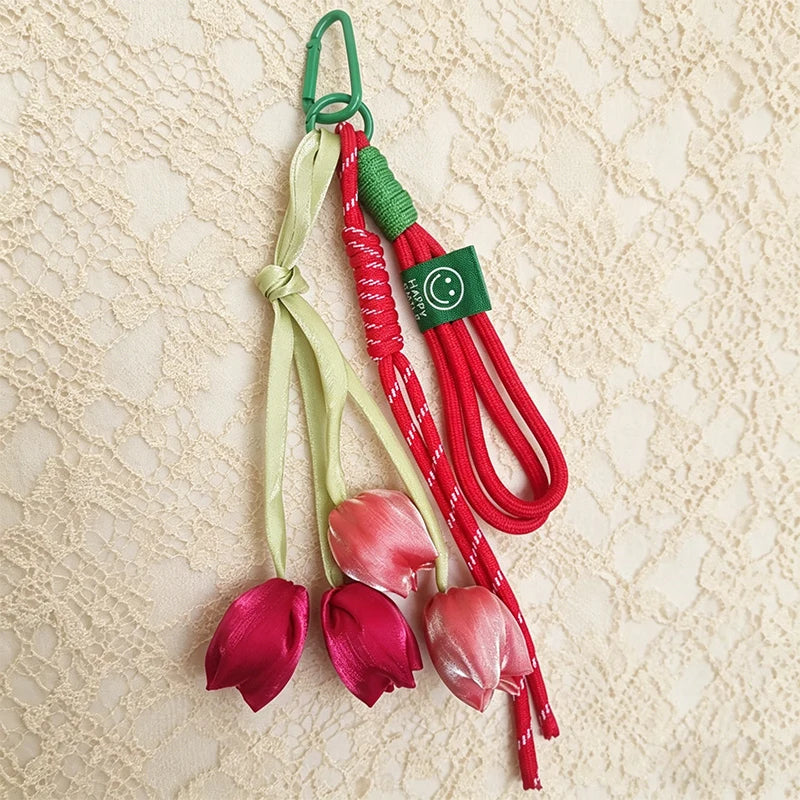 A set of red and green tassel bag charms featuring tulip flower shapes on a light background.
