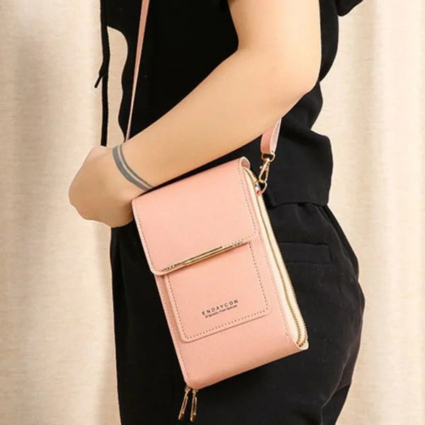 A light pink women's touch screen crossbody shoulder bag carried by a person wearing a black top and pants.