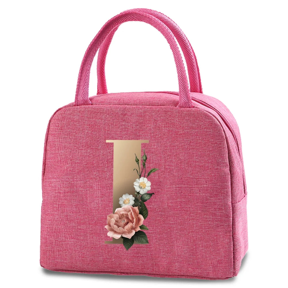 A pink insulated canvas lunch bag featuring a gold letter 'T' and floral embroidery.