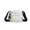 A light beige patterned water resistant crossbody shoulder bag with black strap and orange accents.