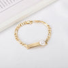 A gold-colored chain bracelet with a smiling face charm on a white background.