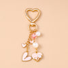 Gold-toned pearl bow heart keychain with a heart-shaped clasp and dangling pearls