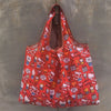 A bright orange reusable shopping bag with a pattern of cute characters and designs hanging against a gray background.