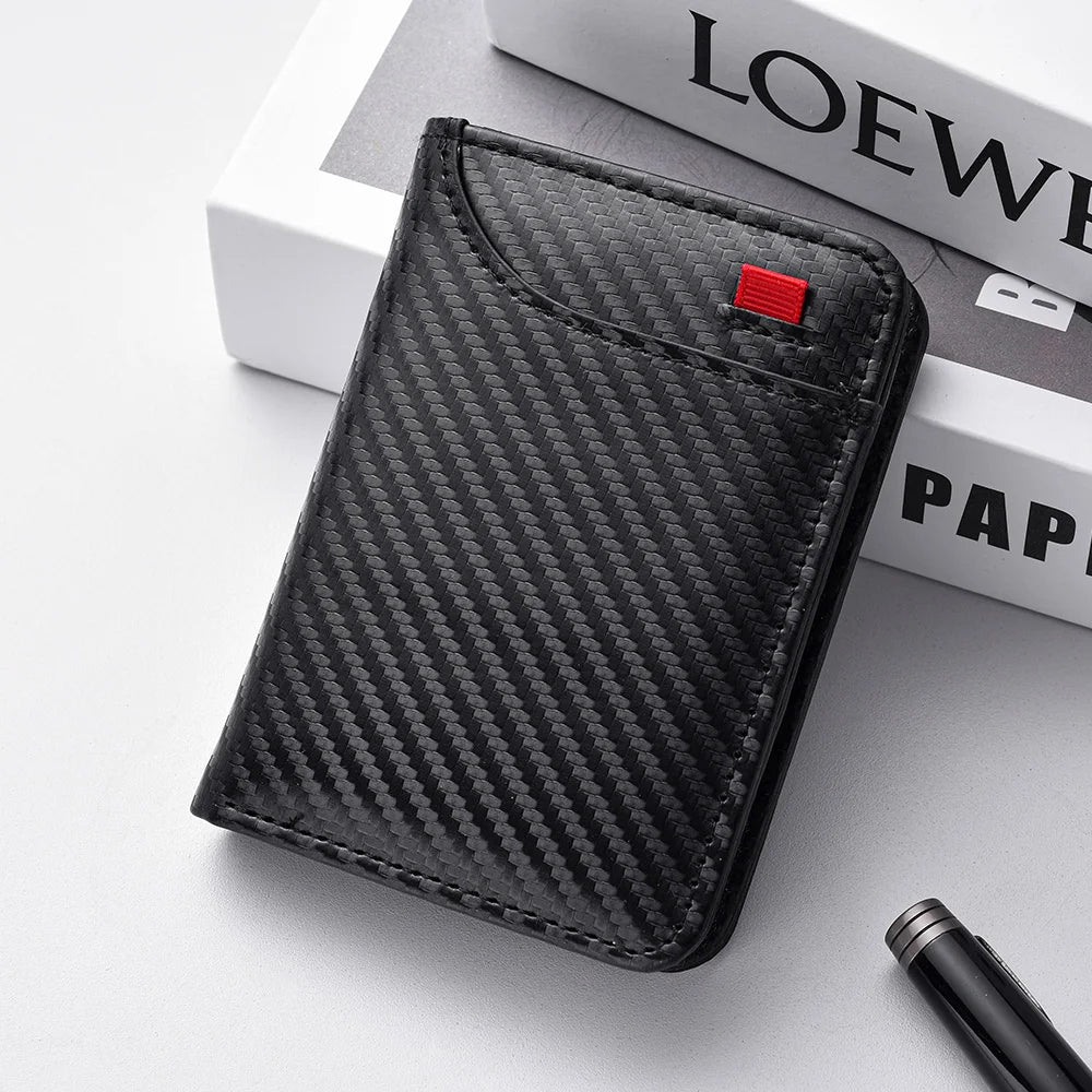 A black carbon fiber texture slim bi-fold wallet resting on a white surface next to a book.