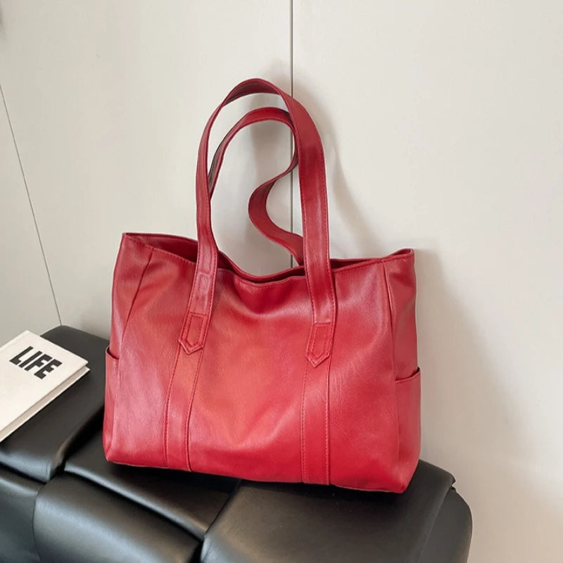 A red vintage-style zip-top tote bag made of durable vegan leather resting on a black surface.