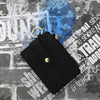 Black PU leather card holder wallet with a gold bangle and tassel resting on a textured surface.