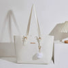 Bolso de hombro de cuero PU color crema con tirantes beige claro y un charm de pompom esponjoso.
