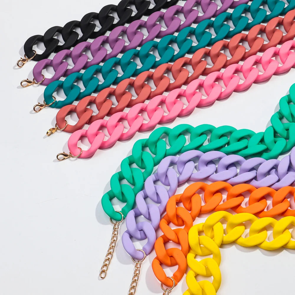 A display of colorful matte acrylic choker necklaces in various shades including black, purple, teal, pink, and orange.