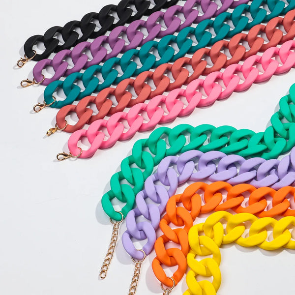 A display of colorful matte acrylic choker necklaces in various shades including black, purple, teal, pink, and orange.