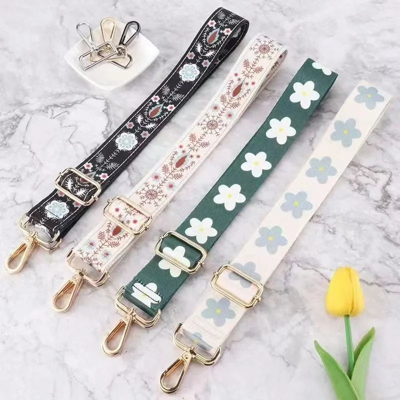 A collection of adjustable nylon bag straps in various patterns and colors laid out on a marble surface.