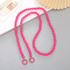 Pink acrylic bead cross phone charm necklace laid on a gray surface with a light background.