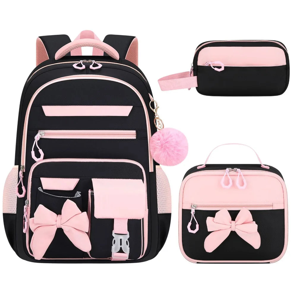 A set of three pink and black cartoon school bags for girls, including a backpack and two small pouches.