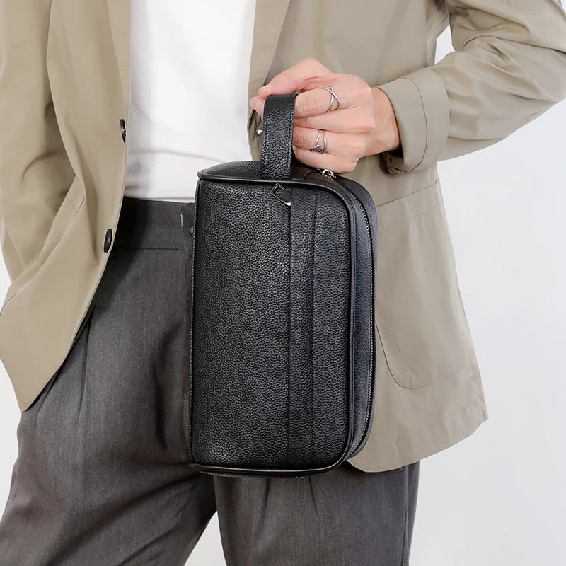 A woman holds a black PU leather crossbody bag against a light beige jacket and gray pants.