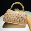 A gold-toned crystal-embellished clutch bag with a chain strap resting on a white surface.