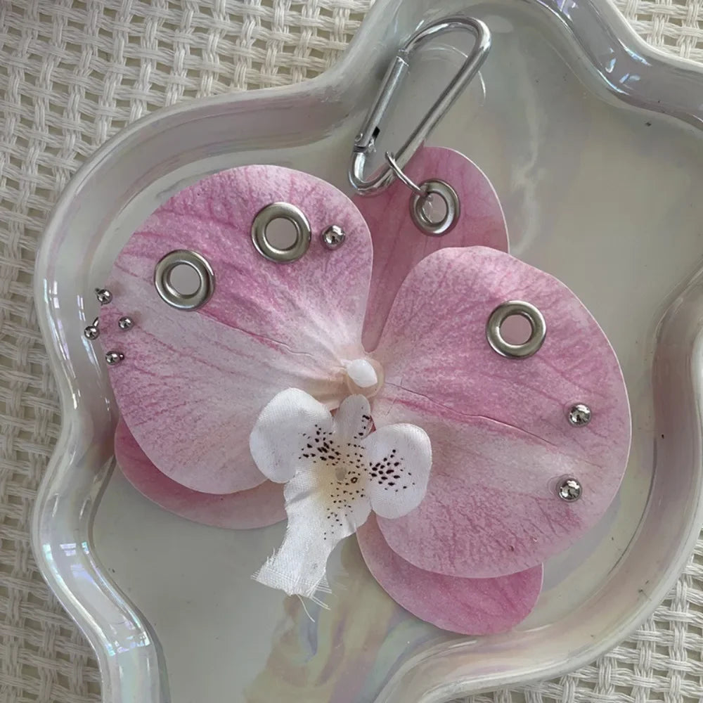 A realistic pink orchid flower is attached to a silver keychain ring.