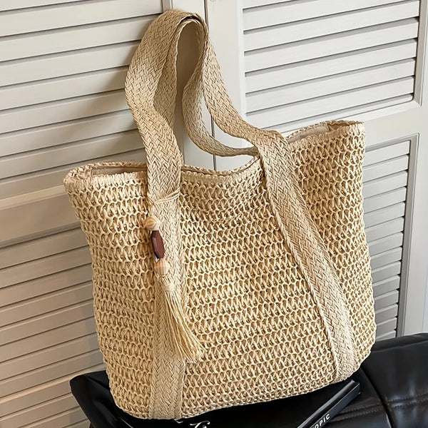 Natürliche Strohtasche mit geflochtenem Riemen vor weißer, lamellierter Fläche.