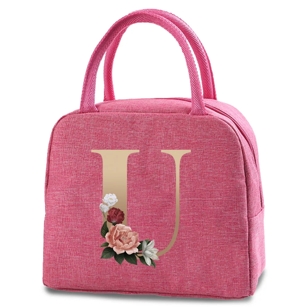 A pink insulated canvas lunch bag featuring a gold letter U and floral embroidery.