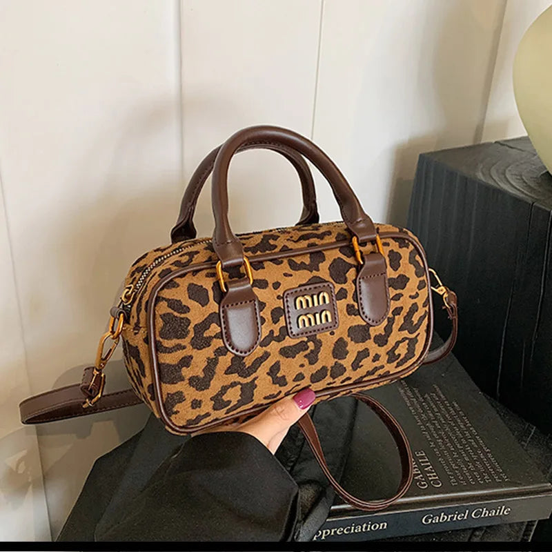 Braune Leopardenmuster-Designer-Hobo-Tasche mit Ledergriffen auf dunkler Oberfläche.