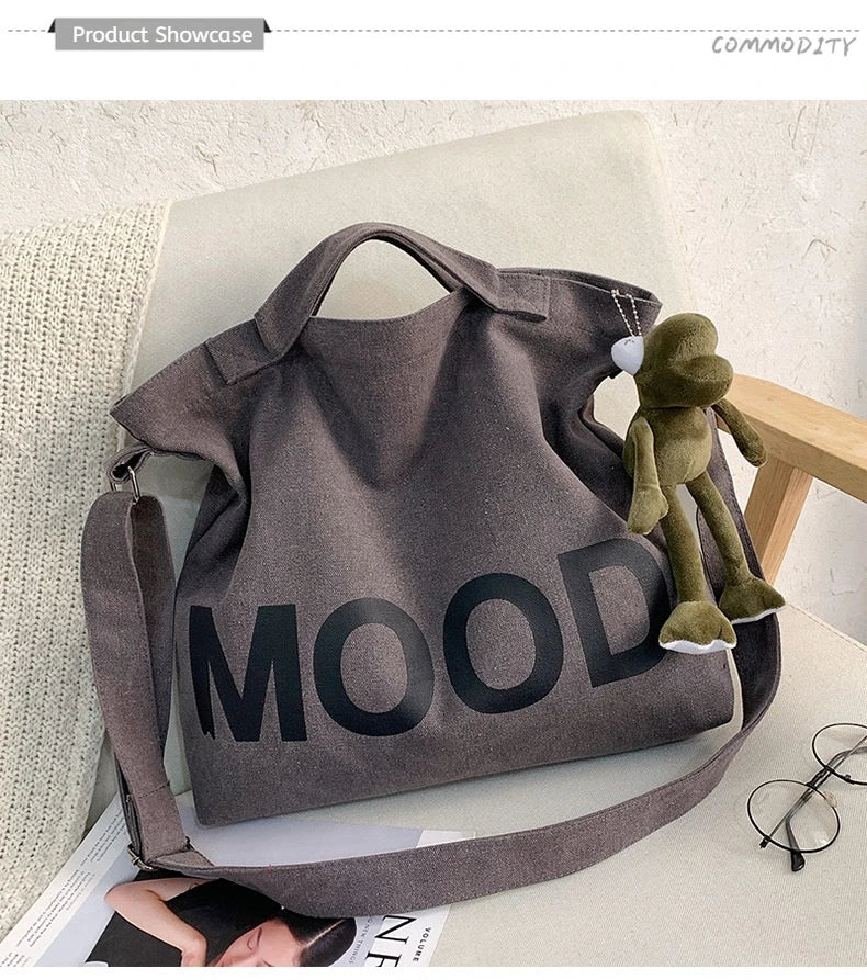 A dark gray canvas tote bag featuring the word MOOD printed in large, black letters.