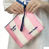 Bolsa cosmética de neopreno impermeable a rayas rosa y blanco con cordón azul en la mano de una persona
