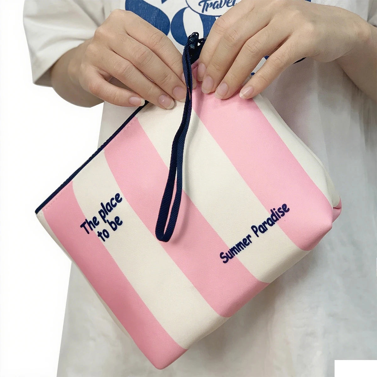 Bolsa cosmética de neopreno impermeable a rayas rosa y blanco con cordón azul en la mano de una persona