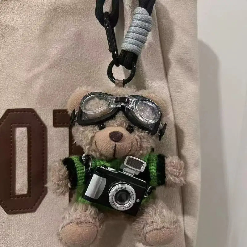A plush bear keychain featuring glasses and a camera attached to a black carabiner.
