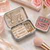 A portable metal storage box with a sardine print design holds gold and pearl jewelry.