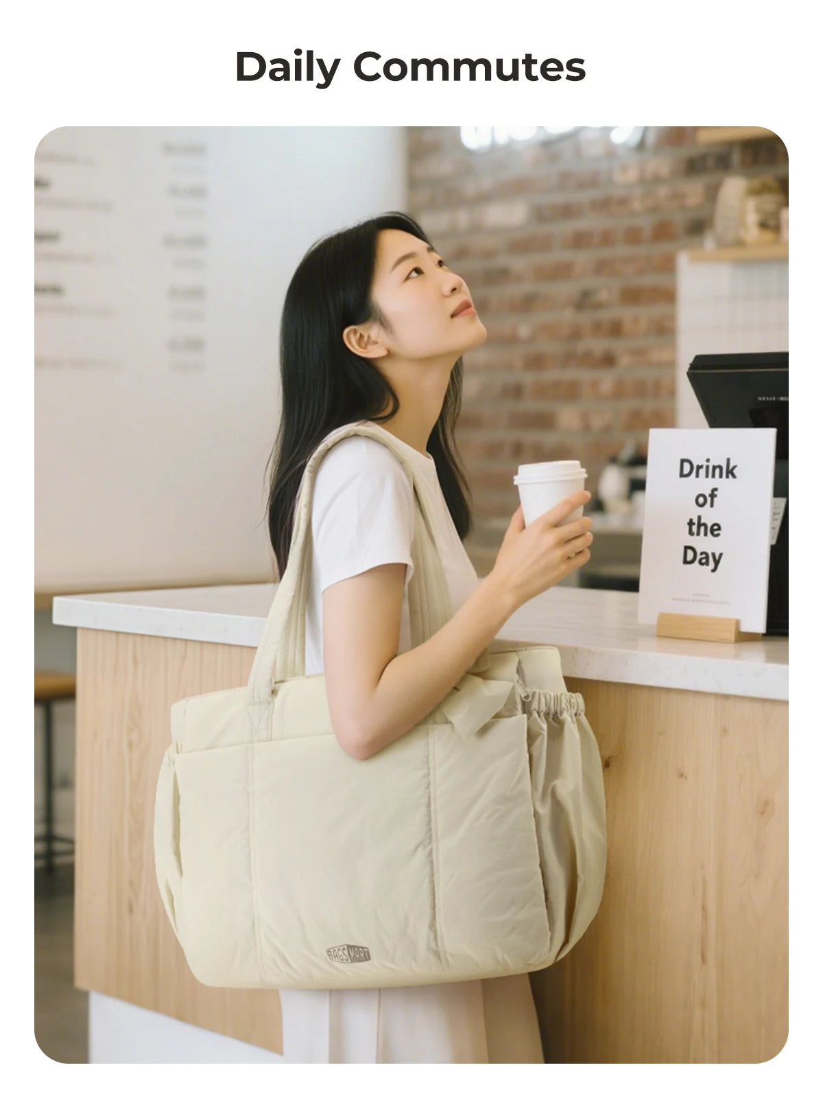 A woman carrying a beige large capacity tote bag and a coffee cup while commuting.