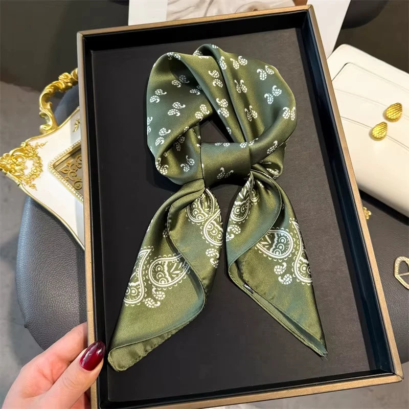 A dark olive green paisley silk hair scarf and headband displayed in a black frame.